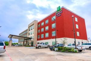 een rood gebouw met auto's geparkeerd op een parkeerplaats bij Holiday Inn Express & Suites - Houston IAH - Beltway 8, an IHG Hotel in Houston