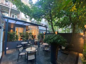 d'une terrasse avec des tables, des chaises et un arbre. dans l'établissement Alp Hotel, à Amsterdam