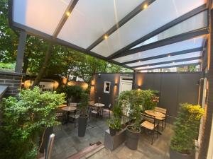 un patio avec des tables et des chaises sous une pergola dans l'établissement Alp Hotel, à Amsterdam