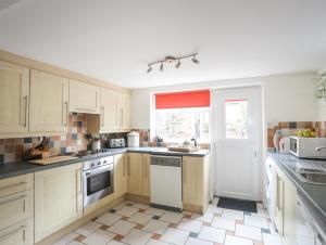 a kitchen with white cabinets and a sink and a window at Pen Dinas in Bangor