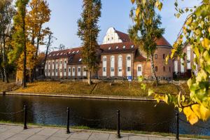 um edifício com uma vedação em frente a uma massa de água em Hotel St. Bruno em Giżycko