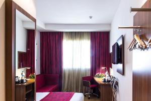 a hotel room with a bed and a desk and a window at Ramada Encore By Wyndham Tangier in Tangier