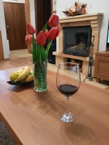 een glas wijn en een vaas met rode tulpen op een tafel bij Lusi Holiday, Смолянски езера in Smolyan