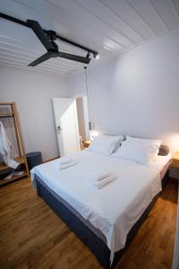 1 dormitorio con 1 cama blanca grande y ventilador de techo en Porto Enetiko, en Nafpaktos