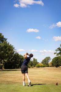 un hombre balanceando un palo de golf en un campo en Avisford Park Hotel, en Arundel