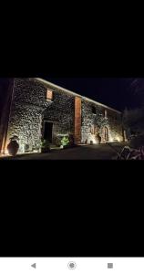 un edificio de piedra con luces en el lateral. en Case Cordovani, en Magliano in Toscana