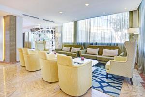 a lobby with yellow chairs and couches in a room at Grupotel Acapulco Playa - Adults Only in Playa de Palma