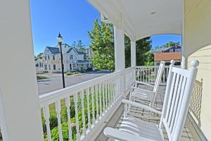 un porche con 2 sillas blancas y vistas a la calle en Grant Street Inn - Bloomington, en Bloomington