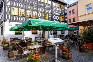 un restaurant avec un parasol vert en face d'un bâtiment dans l'établissement Watzdorfer Geleitschenke und Herberge, à Weimar