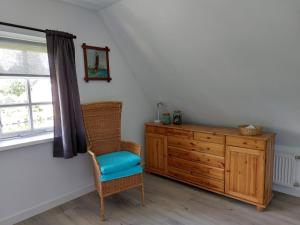 a room with a chair and a dresser and a window at Bed en Boomgaard in Giethoorn