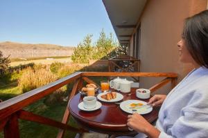 une femme assise sur un balcon avec une table et de la nourriture dans l'établissement Casa Andina Premium Puno, à Puno