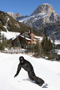 mężczyzna jeżdżący na snowboardzie po śniegu pokrytym stoku w obiekcie Piz Alpin B&B w mieście Colfosco