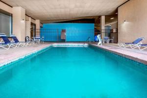 einen Pool mit blauen Stühlen und Stühlen in einem Gebäude in der Unterkunft Days Inn & Suites by Wyndham Clovis in Clovis