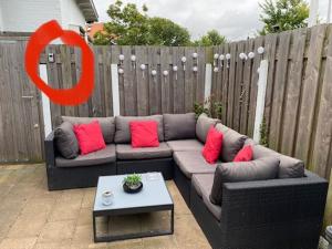 a couch with red pillows sitting on a patio at Queens Beachhouse in Zandvoort