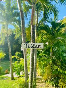 een straatbord voor enkele palmbomen bij Villa Gaïa - Bungalow Ti-Zen et son jacuzzi niché dans un jardin tropical, séjour en amoureux in Le Diamant