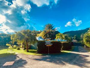 een straatbord in een park met palmbomen bij Villa Gaïa - Bungalow Ti-Zen et son jacuzzi niché dans un jardin tropical, séjour en amoureux in Le Diamant