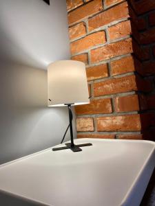 a lamp on a table in front of a brick wall at Apartament Odrzanka in Gryfino