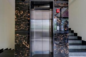 a metal elevator in a building with a staircase at Itsy Hotels NRM Residency in Mysore