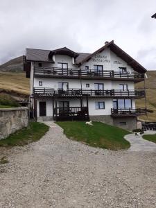 een groot wit gebouw aan de zijkant van een heuvel bij Cabana Transalpina in Ranca