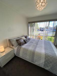 a bedroom with a large bed and a large window at ENTIRE HOME IN WERRIBEE,BEST POSSIBLE LOCATION YOU CAN FIND in Werribee