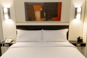 - une chambre avec un lit blanc, 2 tables de nuit et un téléphone dans l'établissement Aston Denpasar Hotel & Convention, à Denpasar