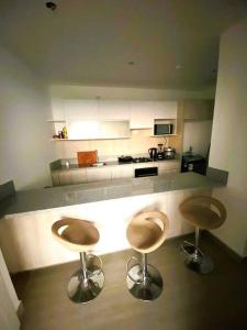 una cucina con due sgabelli al centro di un bancone di Hermoso apartamento en Ocean Reef San Bartolo, con acceso piscina y área sociales! a San Bartolo