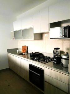 una cucina con armadi bianchi e piano cottura di Hermoso apartamento en Ocean Reef San Bartolo, con acceso piscina y área sociales! a San Bartolo