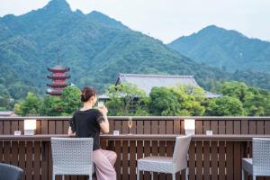 Eine Frau auf einem Balkon mit Bergblick in der Unterkunft Kinsuikan in Miyajima