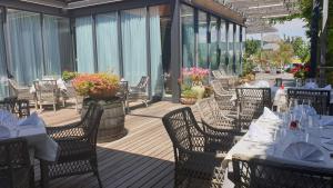 a restaurant with white tables and chairs on a deck at Safir Hotel Casino in Sežana