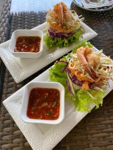 dois pratos brancos de comida com sanduíches e molhos de molho em Bintang Bungalow em Nusa Penida