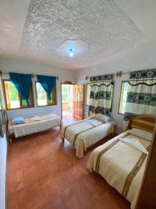 two beds in a room with blue curtains at El Mirador de Tansu in Lanquín