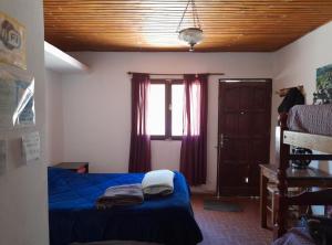 um quarto com uma cama azul e uma janela em ElPoro em Purmamarca