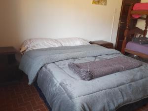 uma cama com um cobertor cinzento e almofadas em ElPoro em Purmamarca