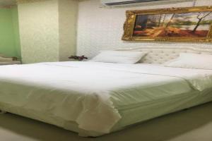 a white bed in a bedroom with a picture on the wall at Capital O 141 Golden Rays Hotel in Ibrā