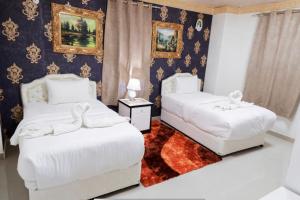 a bedroom with two beds and a rug at Capital O 141 Golden Rays Hotel in Ibrā