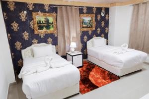 a bedroom with two white beds and a rug at Capital O 141 Golden Rays Hotel in Ibrā