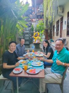 a group of people sitting around a table eating food at Asta House in Kuta