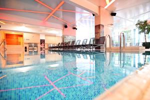 - une piscine avec des chaises dans un bâtiment dans l'établissement Hotel Eger & Park, à Eger