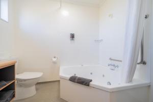 bagno bianco con vasca e servizi igienici di Te Anau Motel & Apartments a Te Anau