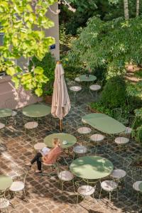 una mujer sentada en una silla junto a las mesas y un paraguas en Hotel des Grandes Ecoles, en París