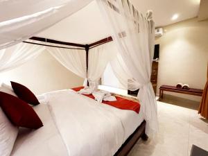 a bedroom with a canopy bed with white curtains at Bali 85 Beach Inn in Padangbai