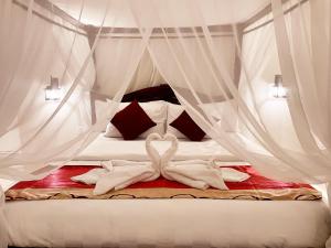 a bedroom with a bed with white drapes at Bali 85 Beach Inn in Padangbai