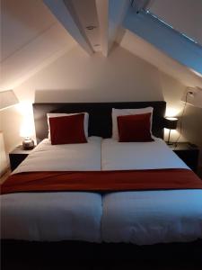 um quarto com uma cama grande e 2 almofadas vermelhas em Bed & Breakfast Trouwborst em Rhenen