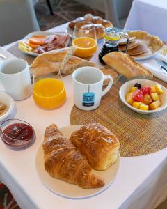 uma mesa com um pequeno-almoço de croissants e sumo de laranja em Kyriad Prestige Beaune le Panorama em Beaune