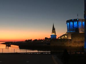 un bâtiment avec une tour d'horloge au coucher du soleil dans l'établissement Appartement Saint Claude - Centre Port, à La Rochelle