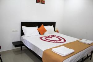 a bedroom with a bed with white sheets and orange pillows at SpiceGreen Homestay,Thekkady in Thekkady