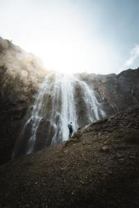 una persona in piedi di fronte a una cascata di Berghotel Engstligenalp ad Adelboden