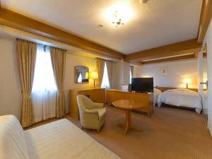 um quarto de hotel com duas camas e uma secretária e uma televisão em Hotel Matsunoka Ichinoseki em Ichinoseki