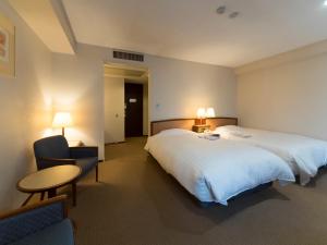 um quarto de hotel com uma cama grande e uma mesa e cadeiras em Hotel Matsunoka Ichinoseki em Ichinoseki