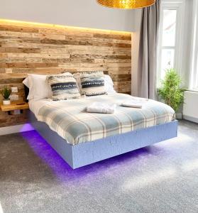 um quarto com uma cama e uma parede de madeira em Cloud9 Guest House - by Coastline Retreats - Newly Renovated, Beautiful Ensuite Rooms Near Seafront in Town Centre, Netflix, SuperFast WiFi, Communal Kitchen em Bournemouth